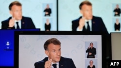 A photo shows monitor screens as France's President Emmanuel Macron speaks during an interview with France 2 and TF1 at the Elysee Presidential Palace.