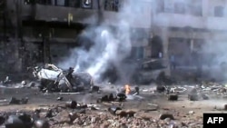 A video grab allegedly shows a burning vehicle and gas cylinders, mainly used for cooking, strewn across a street after a mortar shell struck a gas depot store in the central restive city of Homs on March 20.