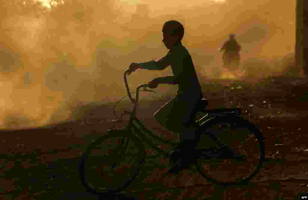 A young Afghan boy rides a bicycle along a road at sunset on the outskirts of Herat. (AFP/Aref Karimi)