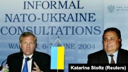 Міністр оборони України Євген Марчук (праворуч) і генеральний секретар НАТО Яап де Хооп Схеффер після підписання меморандуму про взаєморозуміння між НАТО та Україною щодо стратегічного авіаперевезення. Варшава, 7 червня 2004 року