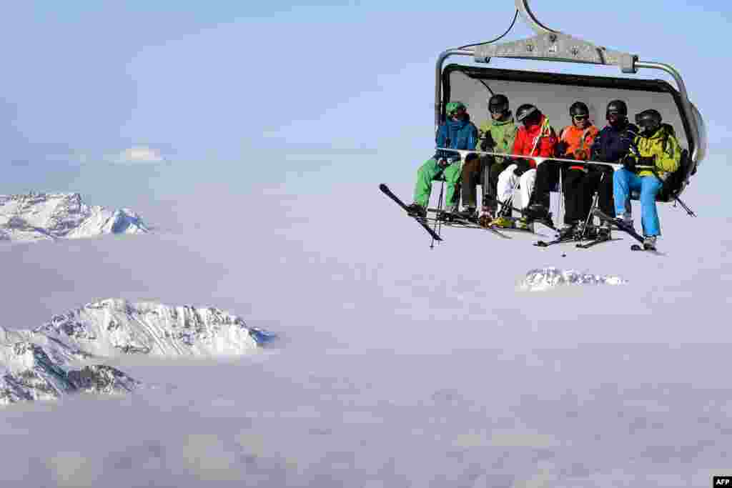 Skiers are seen on a cable car above the fog in the mountains above Engelberg in central Switzerland. (AFP/Fabrice Coffrini)