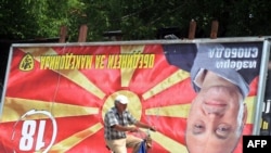 A man rides his bicycle past an upside-down billboard of opposition leader Ljube Boskovski in downtown Skopje