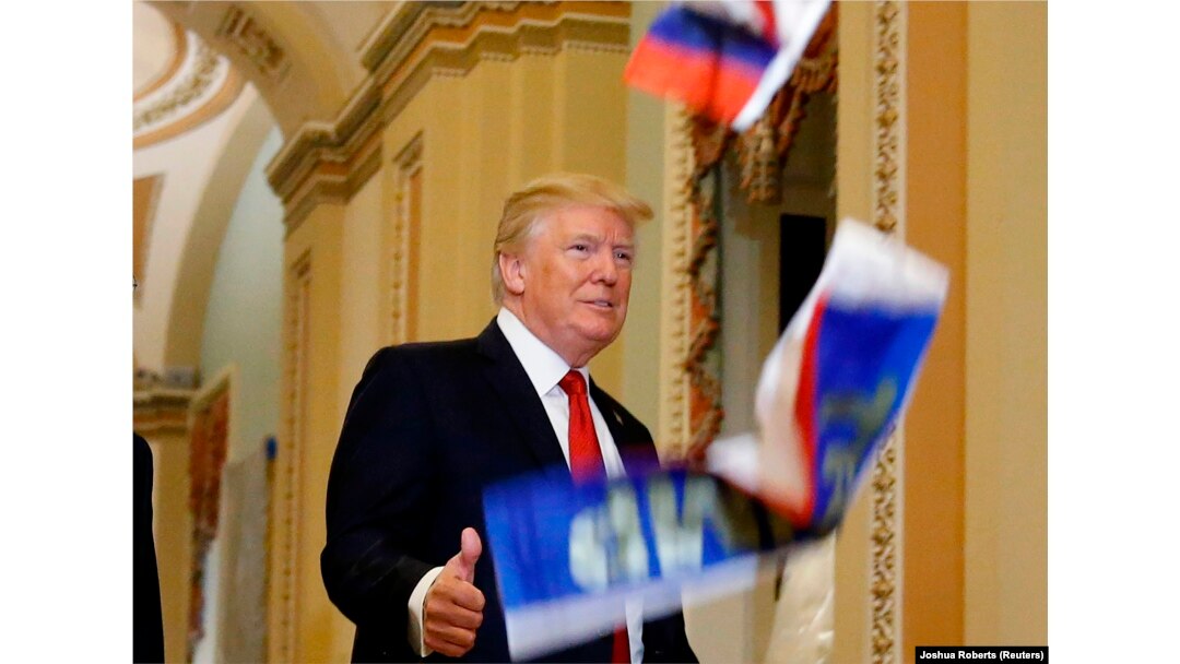 Дональд Трамп обращается к журналистам в Вашингтоне, а кто-то из недовольных им манифестантов кидает в него миниатюрный флаг России. 25 октября 2017 года