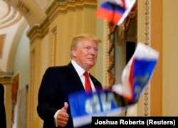 Дональд Трамп обращается к журналистам в Вашингтоне, а кто-то из недовольных им манифестантов кидает в него миниатюрный флаг России. 25 октября 2017 года