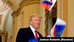 Дональд Трамп обращается к журналистам в Вашингтоне, а кто-то из недовольных им манифестантов кидает в него миниатюрный флаг России. 25 октября 2017 года
