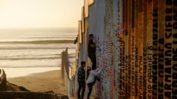 Мужчина пытается перелезть через пограничную стену между Мексикой и США, 24 декабря 2018 года