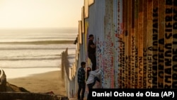 Мужчина пытается перелезть через пограничную стену между Мексикой и США, 24 декабря 2018 года