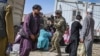 Американски војник вперува оружје кон авганистански патник на аеродромот во Кабул. 16 август 2021 година .