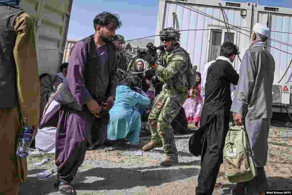 A U.S. soldier points his gun toward an Afghan at the airport in Kabul.&nbsp;