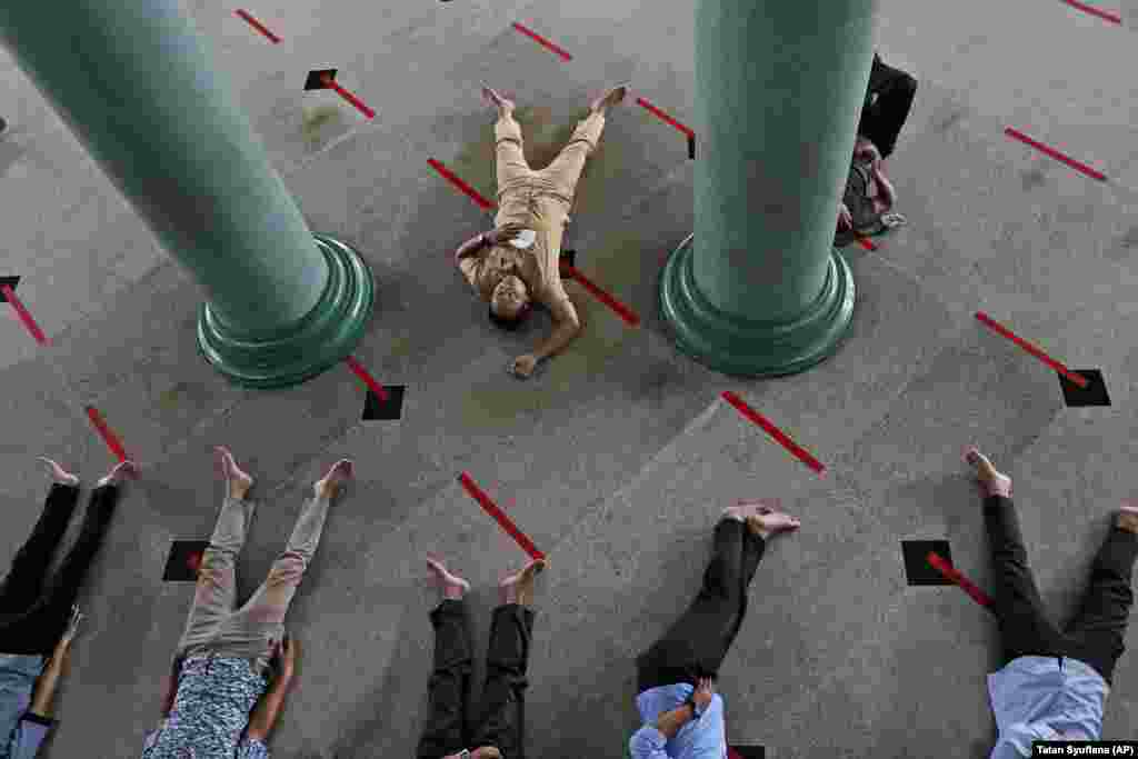 Джакарта, Индонезия. Мужчины лежат на полу мечети, на котором нанесены знаки для соблюдения норм социальной дистанции. В этом году верующие пошли в мечети, в отличие от прошлого года, когда молитвенные дома пустовали &ndash; начало священного месяца в 2020 году пришлось на начало пандемии COVID-19