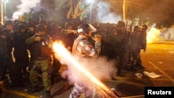 A riot policeman fires his weapon while confronting stone-throwing demonstrators during an antigovernment protest in Belem, Brazil, at the mouth of the Amazon River, on June 20.