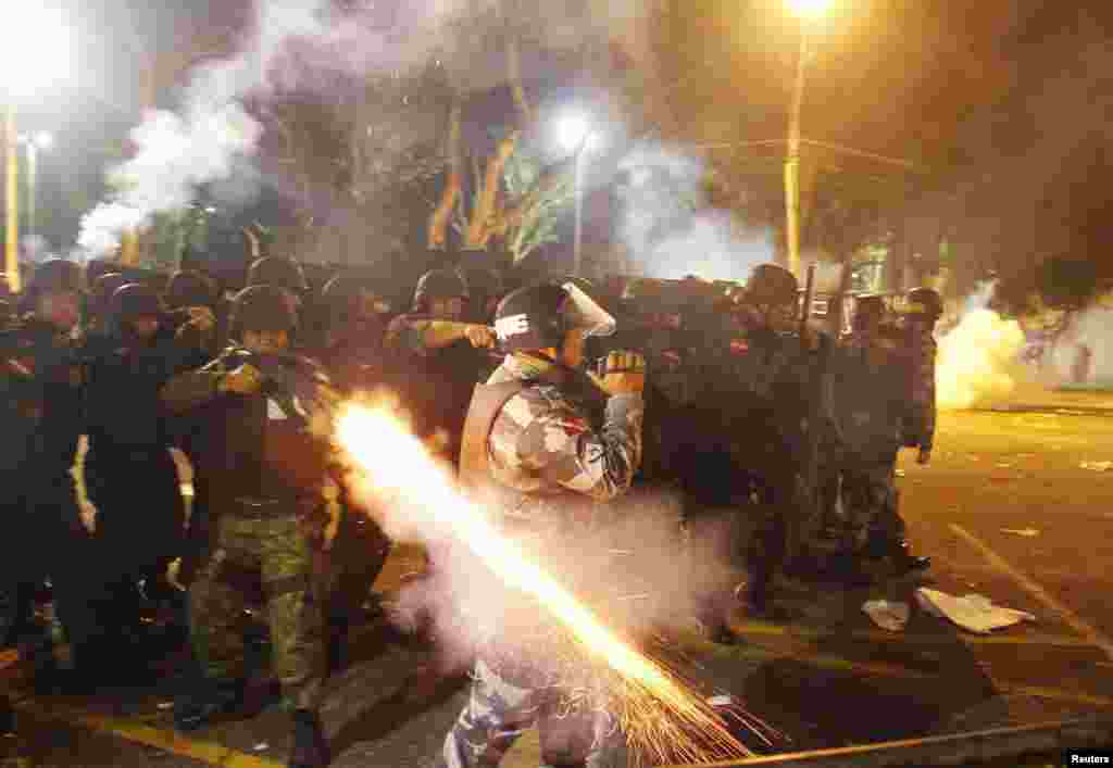 A riot policeman fires his weapon while confronting stone-throwing demonstrators during an antigovernment protest in Belem at the mouth of the Amazon River. Tens of thousands of demonstrators marched through the streets of Brazil&#39;s biggest cities on June 20 in a growing protest that is tapping into widespread anger at poor public services, police violence, and government corruption. (Reuters/Ney Macondes)