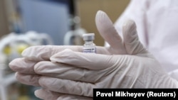  Медицинский работник нагревает флакон с вакциной Спутник V против коронавирусной болезни (COVID-19) перед введением инъекции. Казахстан. 2 апреля 2021 г.