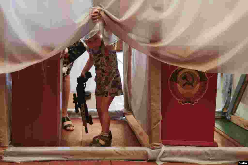 A child looks out as voters fill out ballot papers in booths during voting in the presidential election at a polling station in the northern Ukrainian village of Kodra on May 25. (Reuters/Konstantin Chernichkin)