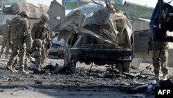 U.S.soldiers inspect the site of a suicide bomb attack near the gate of Kandahar airport.