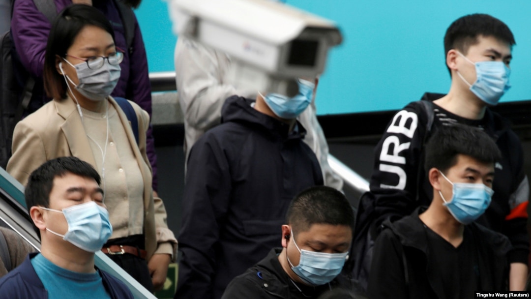 Ljudi koji nose maske za lice u blizini nadzorne kamere unutar stanice podzemne željeznice tokom jutarnje špice u Pekingu u Kini, 7. aprila 2020. godine.