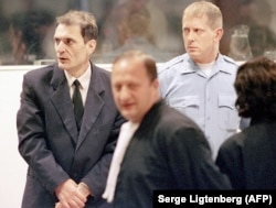 Bosnian Serb Dragoljub Kunarac (left), accused of war crimes, meets his lawyers in the courtroom at the ICTY in The Hague in February 2001.