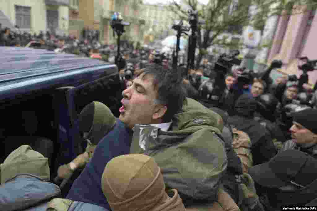 Police force Saakashvili into a police van. The official reason given for his arrest was that he was &quot;plotting&quot; against the Ukrainian authorities with the help of allies financed by exiled former Ukrainian President Viktor Yanukovych.