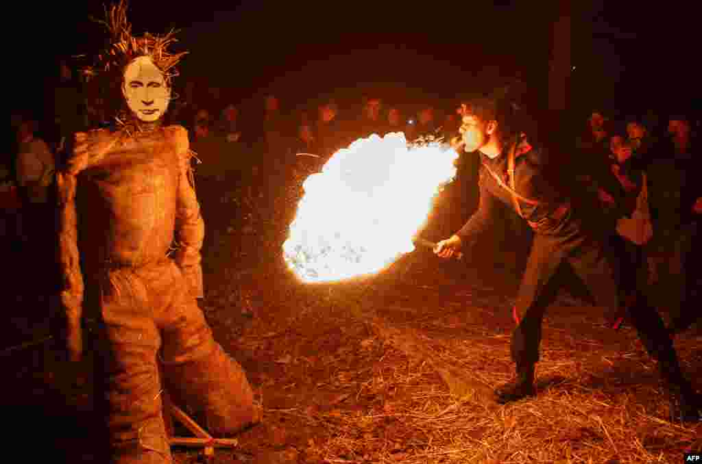 A man blows fire on a scarecrow with a mask depicting Russian President Vladimir Putin during celebrations to say farewell to winter in the western Ukrainian city of Uzhhorod on February 15. (AFP/Alexander Zobin)