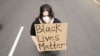 Удзельніца акцыі пратэсту з плякатам Black Lives Matter — «Жыцьці цемнаскурых маюць значэньне»