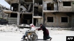 Дамаскідегі соғыстан қираған үйдің жанында кетіп бара жатқан тұрығндар, сирия (Көрнекі сурет).