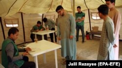 FILE: Afghan men get registered as voters at a voter registration center in Herat.