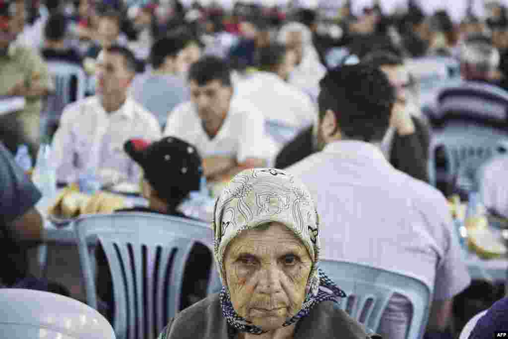 A woman waits to break her fast with a dinner distributed for free during the Muslim fasting month of Ramadan in Pristina. (AFP/Armend Nimani)