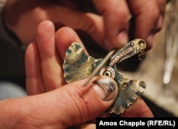 A nearly completed earring made from a bullet that was shaped into a gingko leaf. Tadevosian’s thumb was injured by mishaps with his hammer.