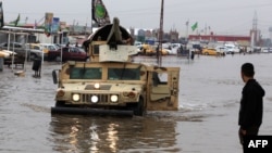 عربة عسكرية وسط شارع في بغداد غمرته الأمطار
