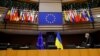 Az európai uniós és az ukrán zászló áll egymás mellett az asztaloknál, háttérben a tagországok zászlói az Európai Parlamentben, Brüsszelben 2022. március 1-jén - képünk illusztráció
