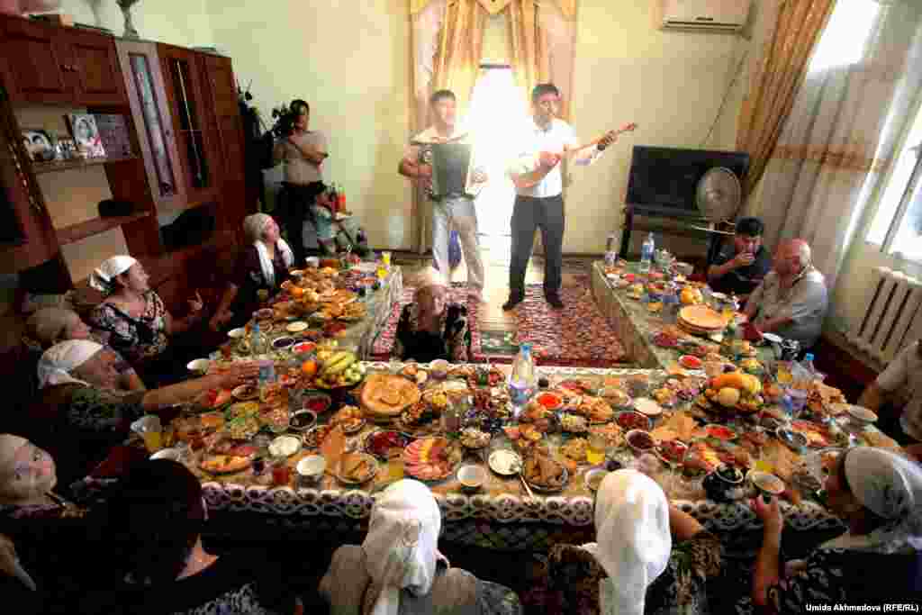 Inlaws and distinguished guests are seated at the head of the table, as two men sing for them.