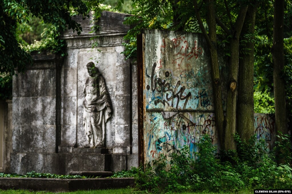 Pjesë e mbetur periferike e Murit të Berlinit qëndron pranë një varri me një figurë të Jezusit, në varrezën e Shën Hedvigut, në Berlin. (28 korrik)
