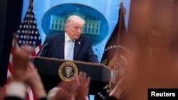 Tramp Ağ evin brifinq otağında mətbuat konfransı keçirir.