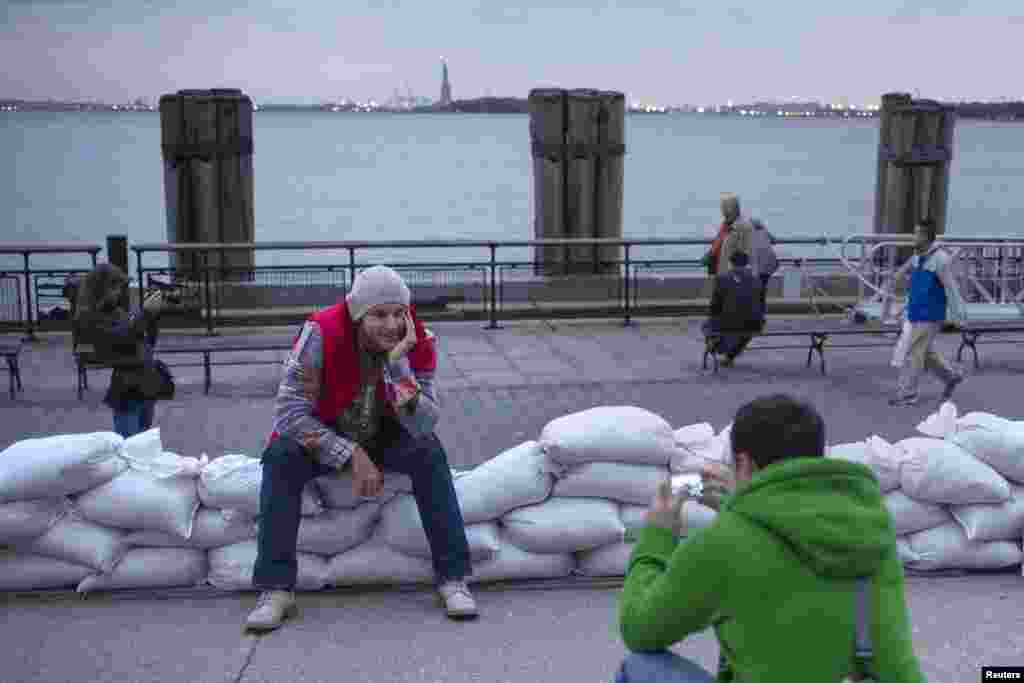 The Statue of Liberty is seen in the background as tourists from Russia pose for pictures on top of sand bags protecting Battery Park in Lower Manhattan, New York.&nbsp;