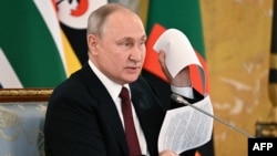 Президент Росії Володимир Путін на зустрічі з делегацією африканських лідерів показує нібито проєкт мирного договору з Україною, який, за його твердженням, був парафований керівником переговорної групи з Києва, 17 червня 2023 року.