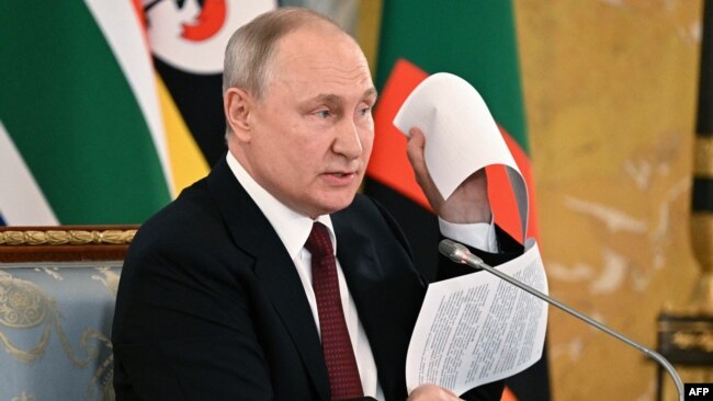 Президент Росії Володимир Путін на зустрічі з делегацією африканських лідерів показує нібито проєкт мирного договору з Україною, який, за його твердженням, був парафований керівником переговорної групи з Києва, 17 червня 2023 року
