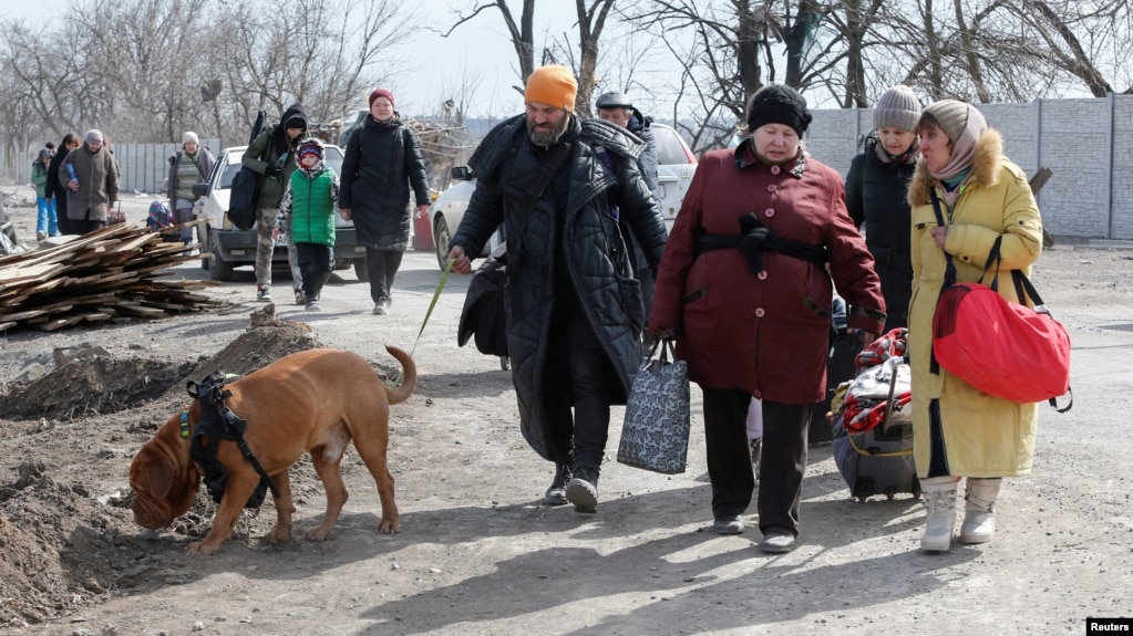 Біженці йдуть вулицею, покидаючи обложене місто Маріуполь 20 березня.