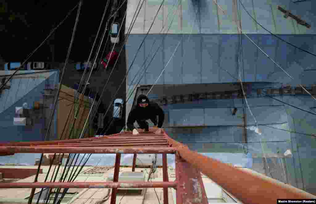 Grigory Shukhov climbs a ladder up to a rooftop in Moscow.