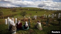 Muslim women in the town of Vlasenica, in an ethnically Serbian part of Bosnia-Herzegovina, sit before a mass funeral in April 2012 for victims of the Bosnian conflict.