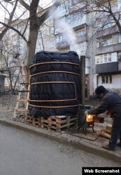 Чоловік обігріває бочку з водою буржуйкою. Донецьк, січень 2025 р.