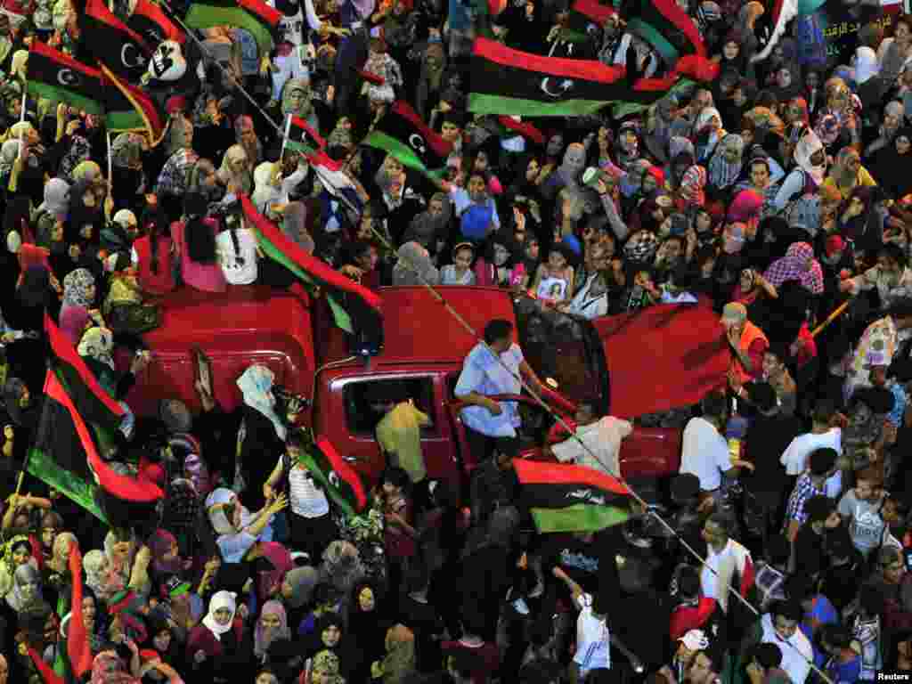 In the eastern city of Benghazi, people wave flags of the Kingdom of Libya, which predated Qaddafi, as they gather near the city's courthouse.