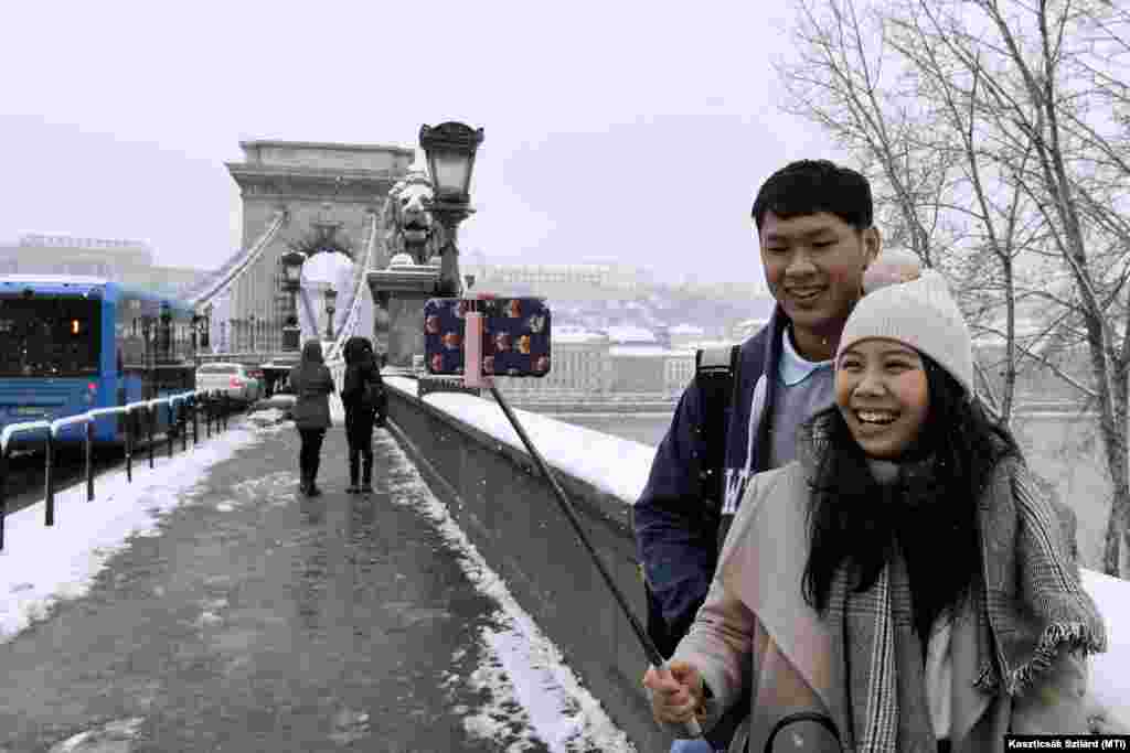 Japán turisták szelfiznek a behavazott Lánchídon.