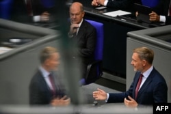 Cancelarul german, Olaf Scholz (centru), privește spre ministrul german de finanțe, Christian Lindner, care ține un discurs în timpul unei sesiuni privind bugetul de stat la Bundestag (camera inferioară a parlamentului), Berlin, 10 septembrie 2024.