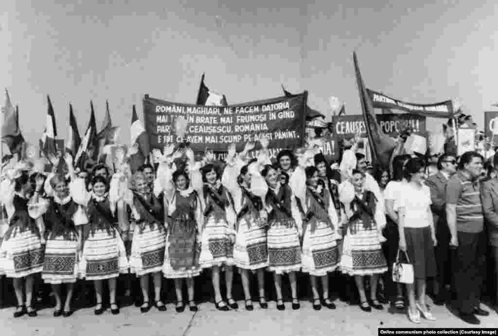 Femeile din nord-vestul județului Bihor, unde trăiește o puternică comunitate etnică maghiară, îl întâmpină pe Ceaușescu. Pe afișele din&nbsp; fundal e scris: &bdquo;Români, marghiari, ne facem datoria, mai tari în brașe, mai frumoși în gând, Partidul, Ceaușescu, România, e tot ce avem mai scump pe acest pământ!&rdquo;