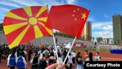Eveniment cultural în China – un vizitator ține în mână steagurile Macedoniei de Nord și Chinei. 