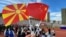 Un participant la un eveniment cultural în China, cu steagurile Macedoniei de Nord și Chinei. 