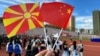 A visitor holds up North Macedonia and Chinese flags at a cultural event in China.