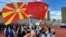 A visitor holds up North Macedonia and Chinese flags at a cultural event in China.