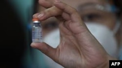A health worker holds up a vial of China's Sinovac COVID-19 vaccine during the first phase of vaccinations for health workers at a hospital in Manila on March 1, 2021. (AFP / Ted Aljibe)