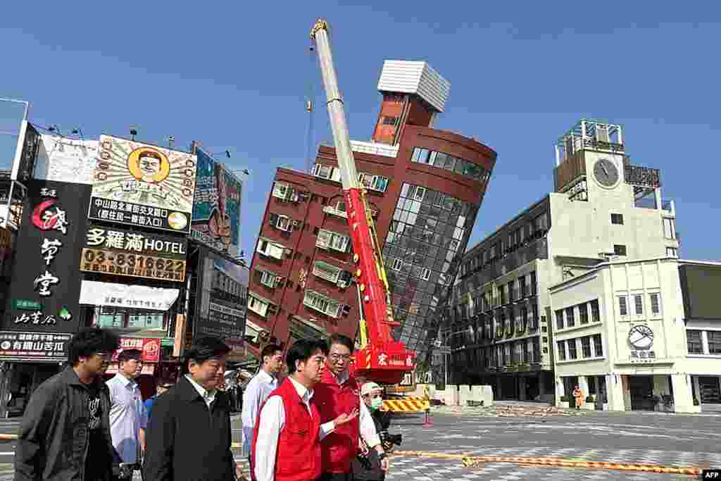 Președintele ales al Taiwanului Lai Ching-te (primul din stânga cu vestă roșie) inspectează pagubele din orașul Hualien, în timp ce în fundal se vede o clădire înclinată, iar în jurul ei un perimetru de siguranță. Taiwan, miercuri, 3 aprilie 2024. Au fost înregistrate cel puțin 76 de replici în mai puțin de cinci ore, cea mai puternică replică având o magnitudine de 6,4 grade, potrivit Administrației Centrale de Meteorologie din Taiwan.